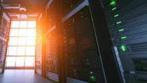 Sunlight filtering into a secure data center with rows of server racks illuminated by green indicator lights, representing modern IT infrastructure and synchronized system uptime.